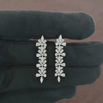 Load and play video in Gallery viewer, Video showcasing the 1.58 CT natural round and tapered baguette cut diamond drop earrings set in 18kt white gold, highlighting their stunning design and brilliant diamond sparkle.
